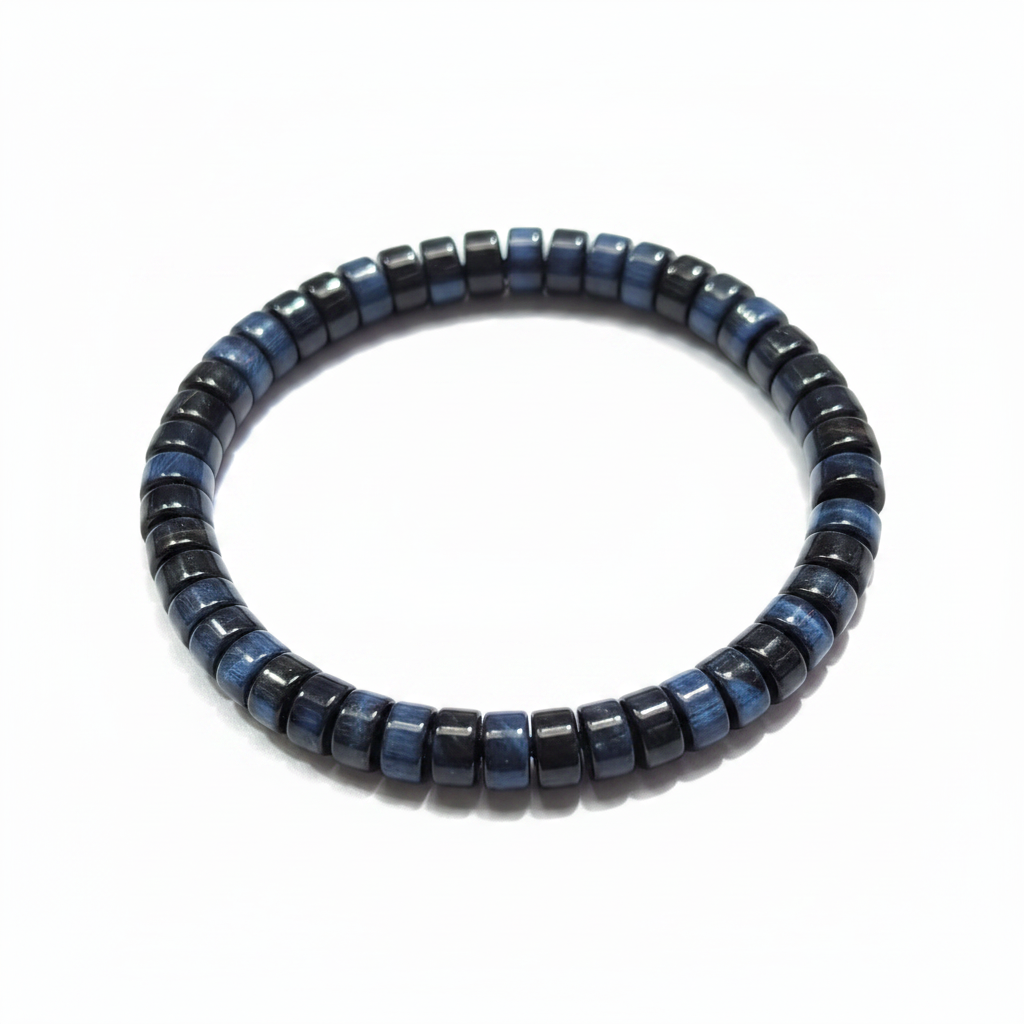 Blue tiger eye bracelet laid in a loose curve with raking light emphasizing the blue chatoyancy across the black faceted beads