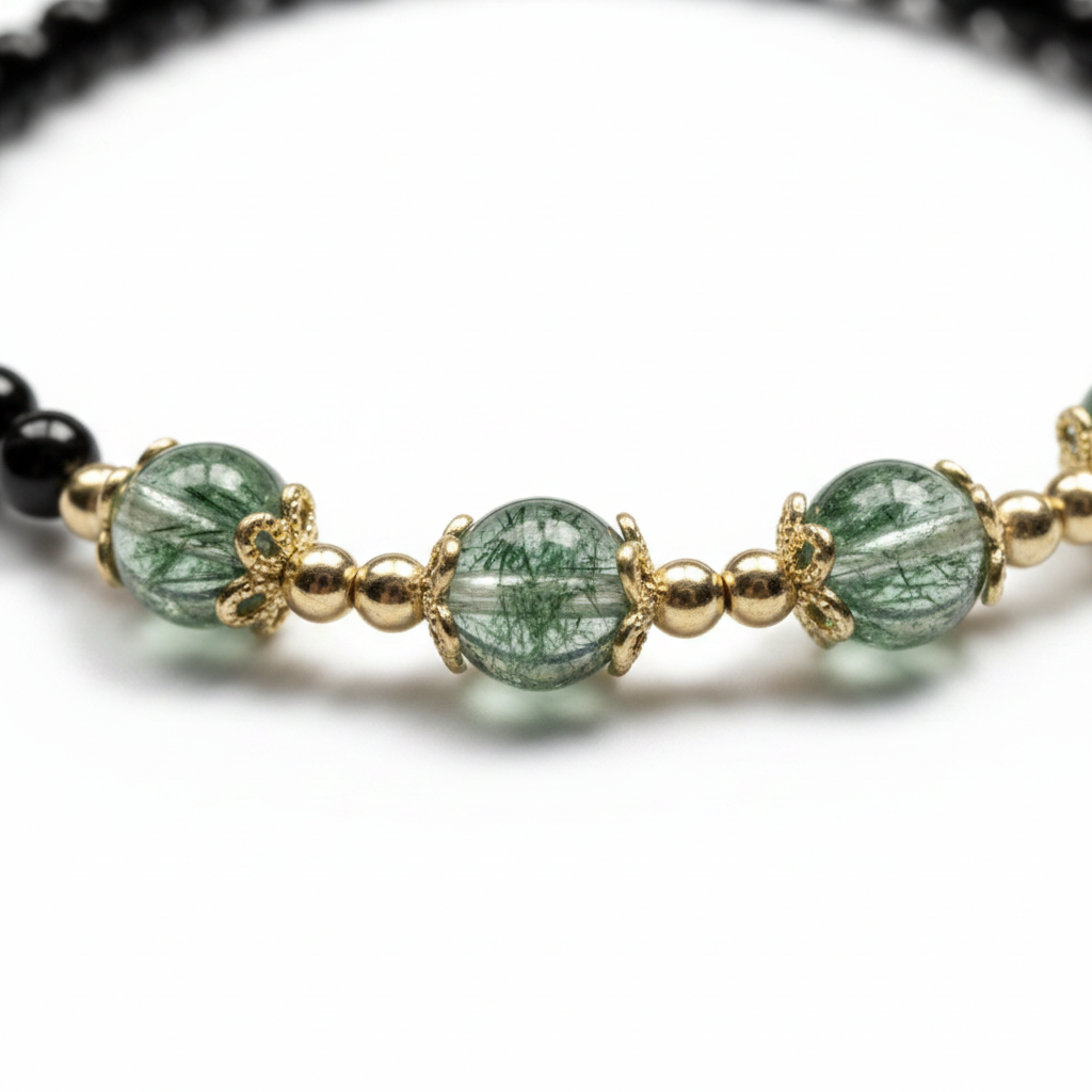Macro detail of black obsidian and green phantom crystal bracelet showing natural inclusions and gold-tone hand-wrapped details